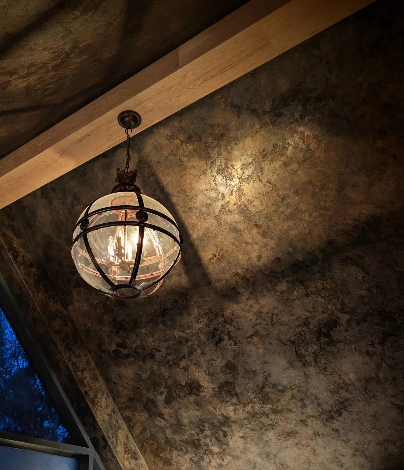 Mottled gold and charcoal surface around a pendant light