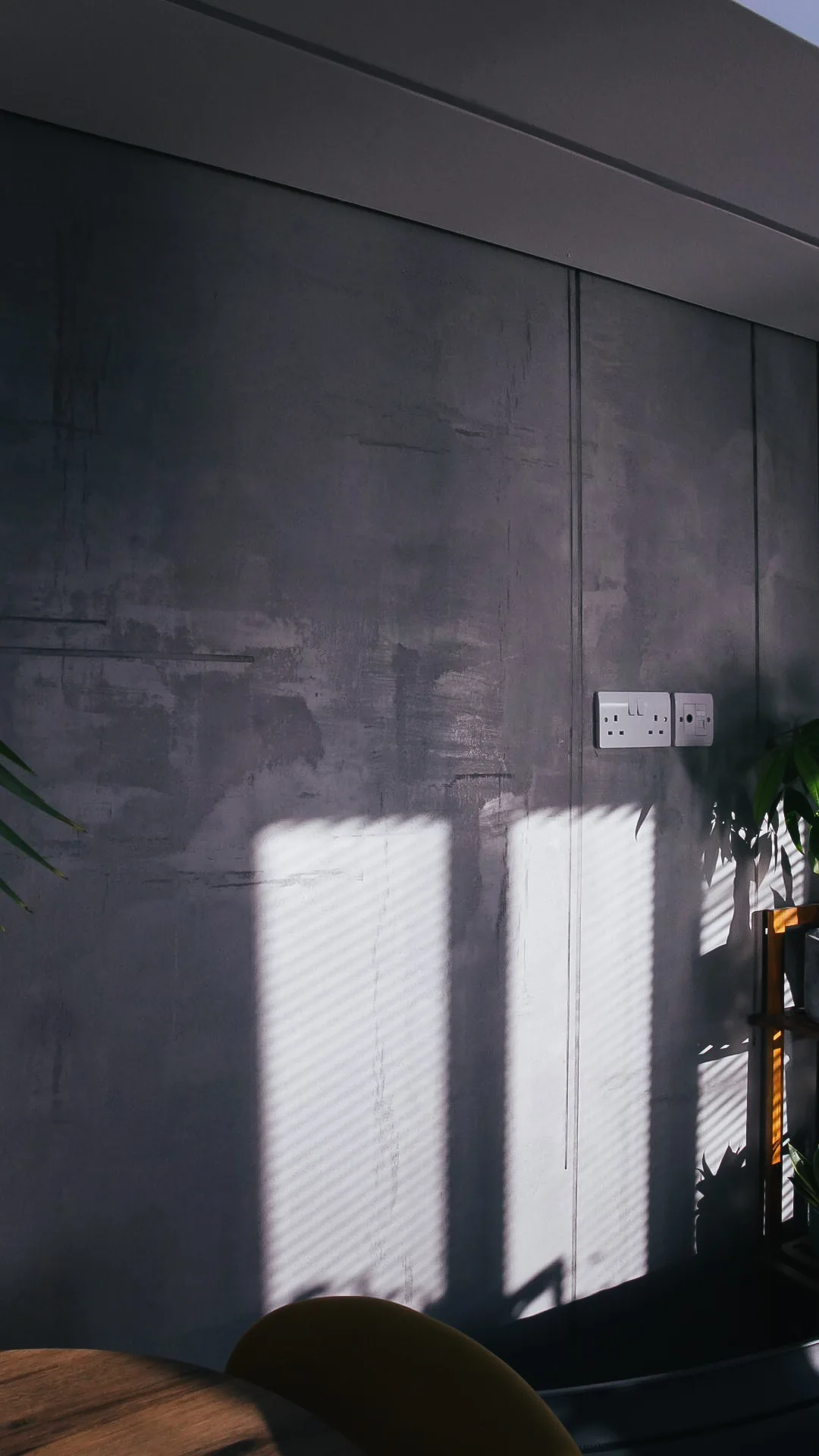 Grey concrete-effect wall in a light-filled interior