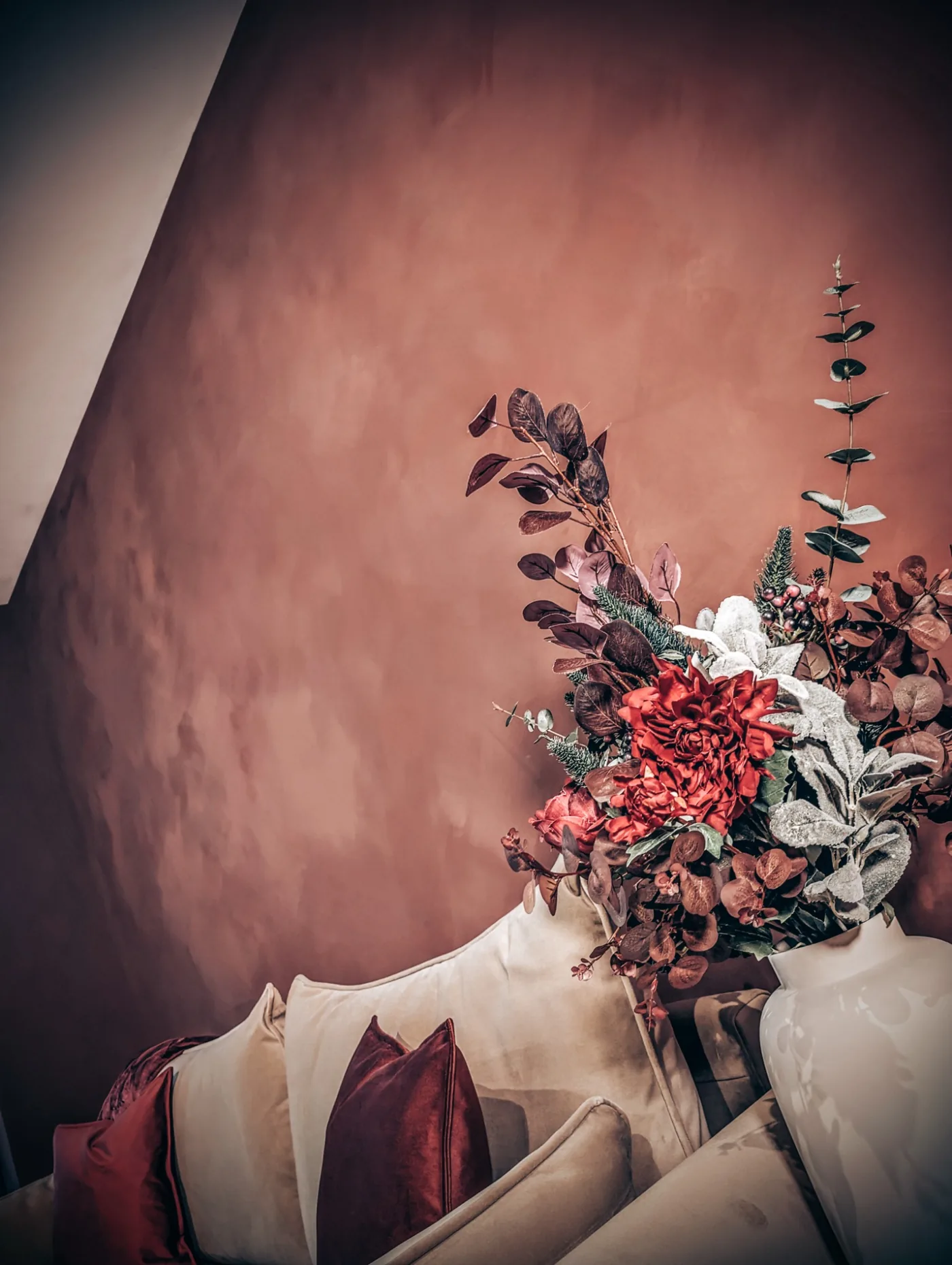 Soft pink decorative wall beside a sofa and flowers