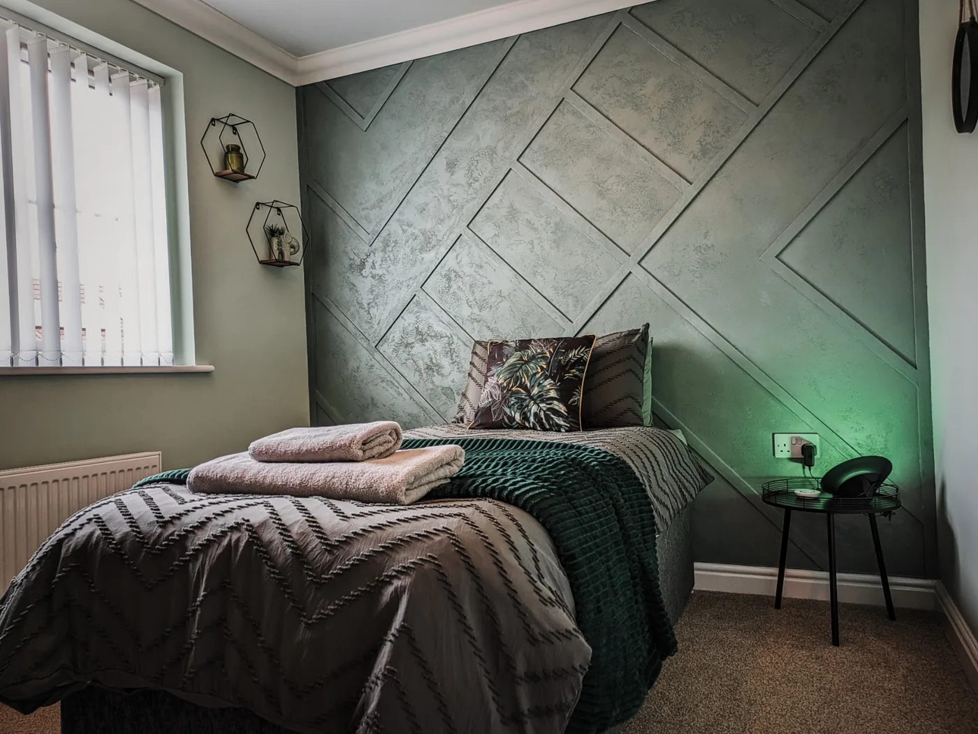 Bedroom with a green geometric feature wall